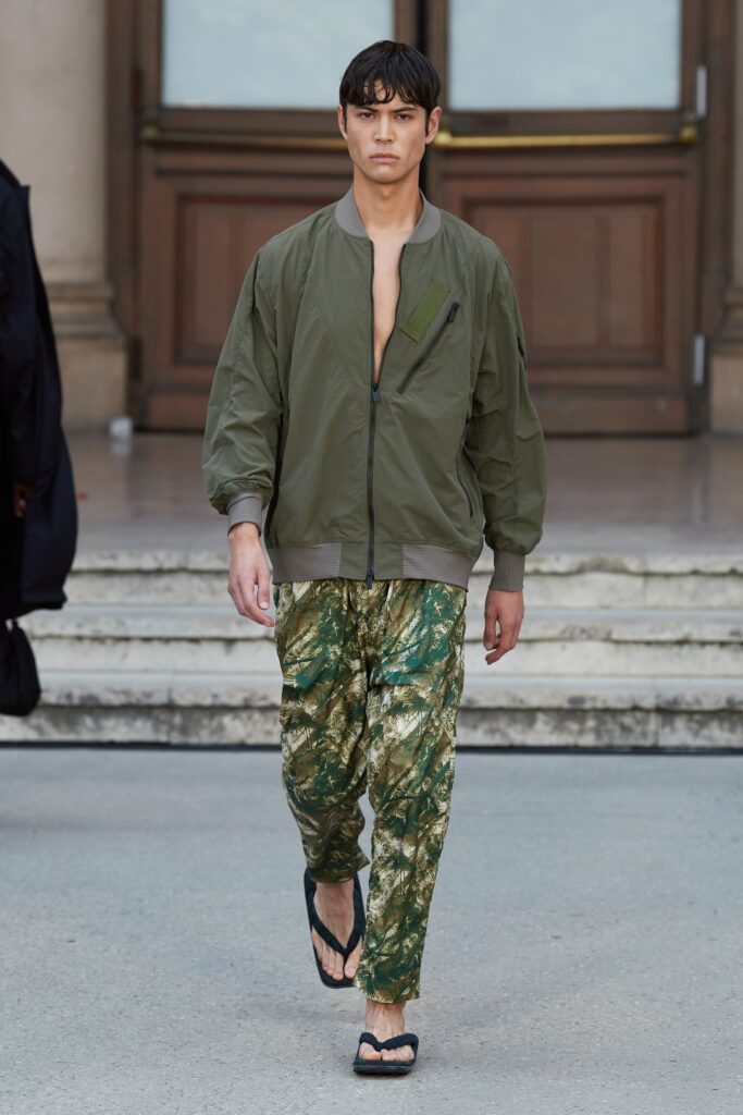 A relaxed green jacket with a collared design paired with multicolored printed pants.