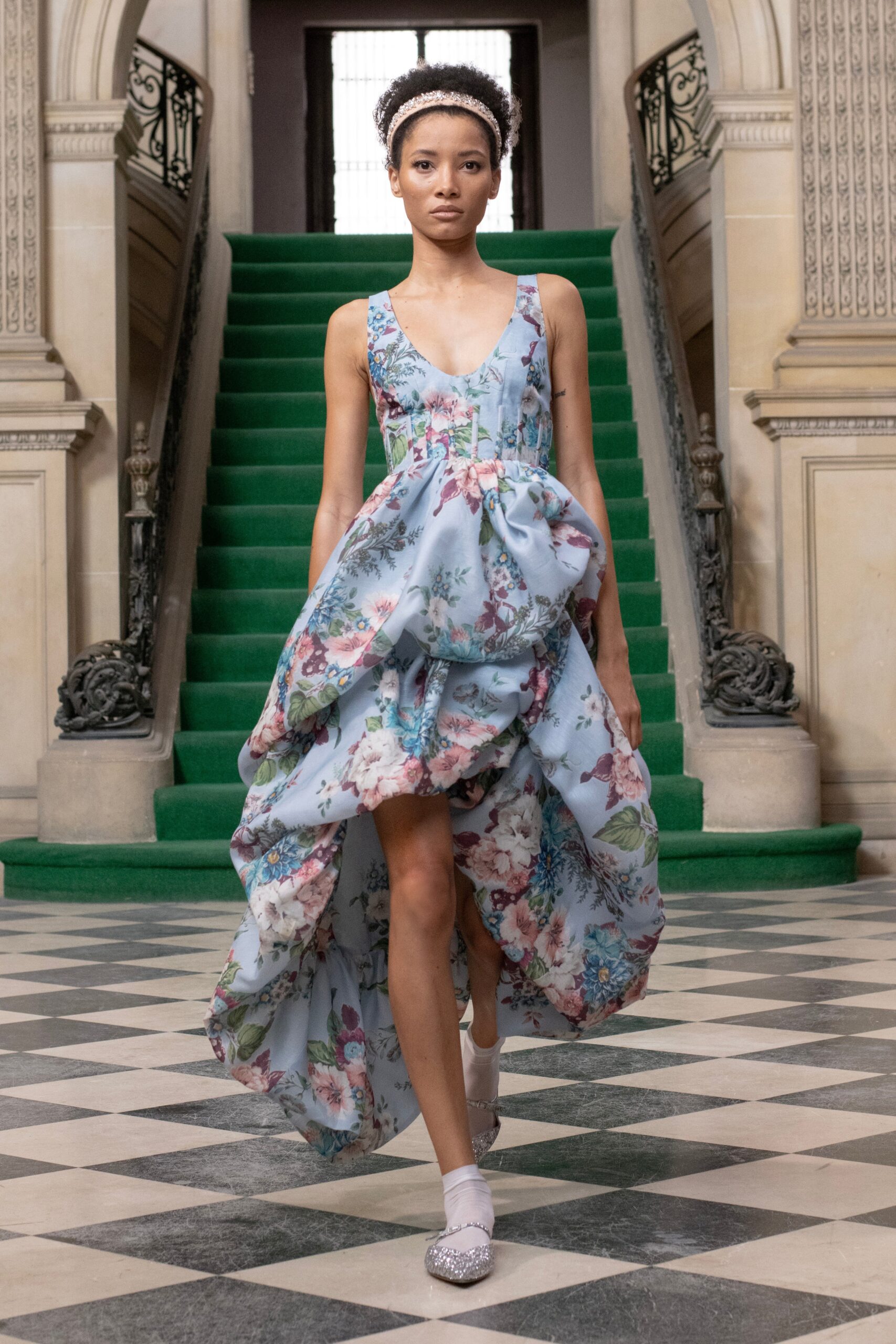 A fitted blue silk sleeveless dress with a V-neckline and tiered silhouette.