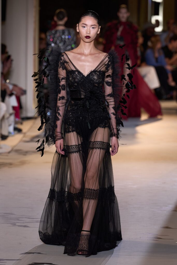 A fitted black lace sleeveless dress with a V-neckline and tiered design details.
