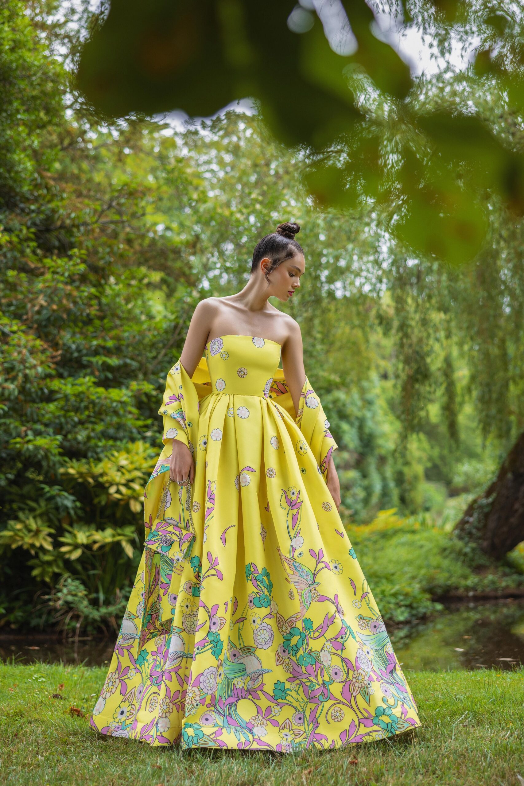 A fitted yellow silk strapless gown with a flared silhouette and intricate floral designs.