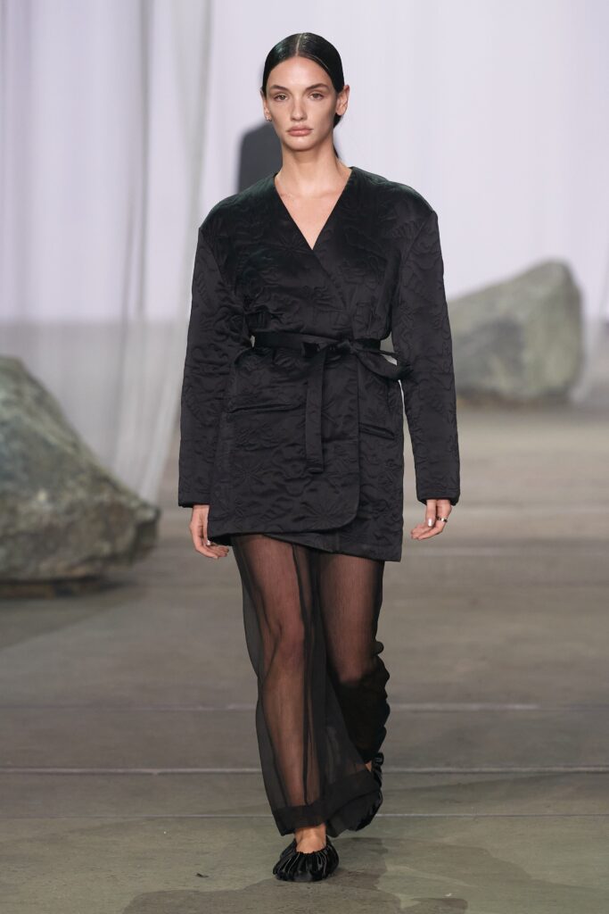 A fitted black silk dress coat with long sleeves and a layered design.