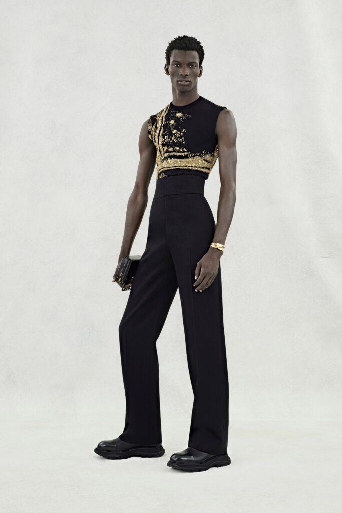 A fitted black silk sleeveless top with gold embroidery paired with straight-leg black pants.