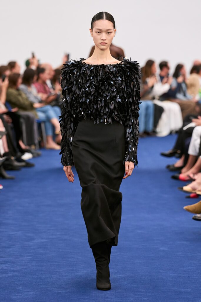 A fitted black silk long-sleeve dress with a high neckline and layered design detail.
