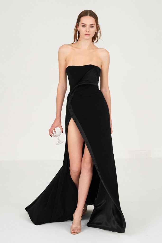 A fitted black silk strapless dress featuring a dramatic slit for an elegant look.