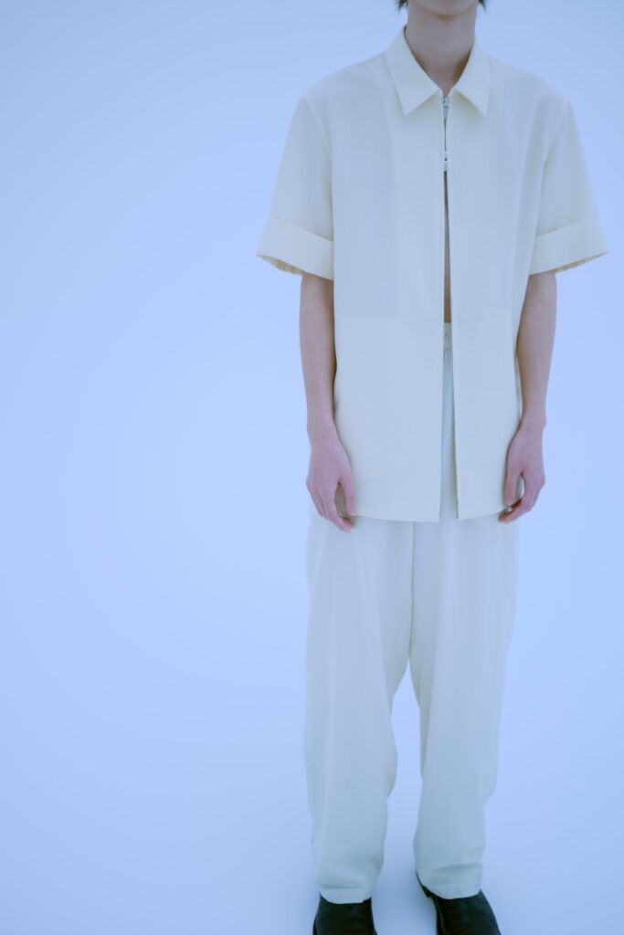 A relaxed white short-sleeve collared shirt paired with straight-leg pants.