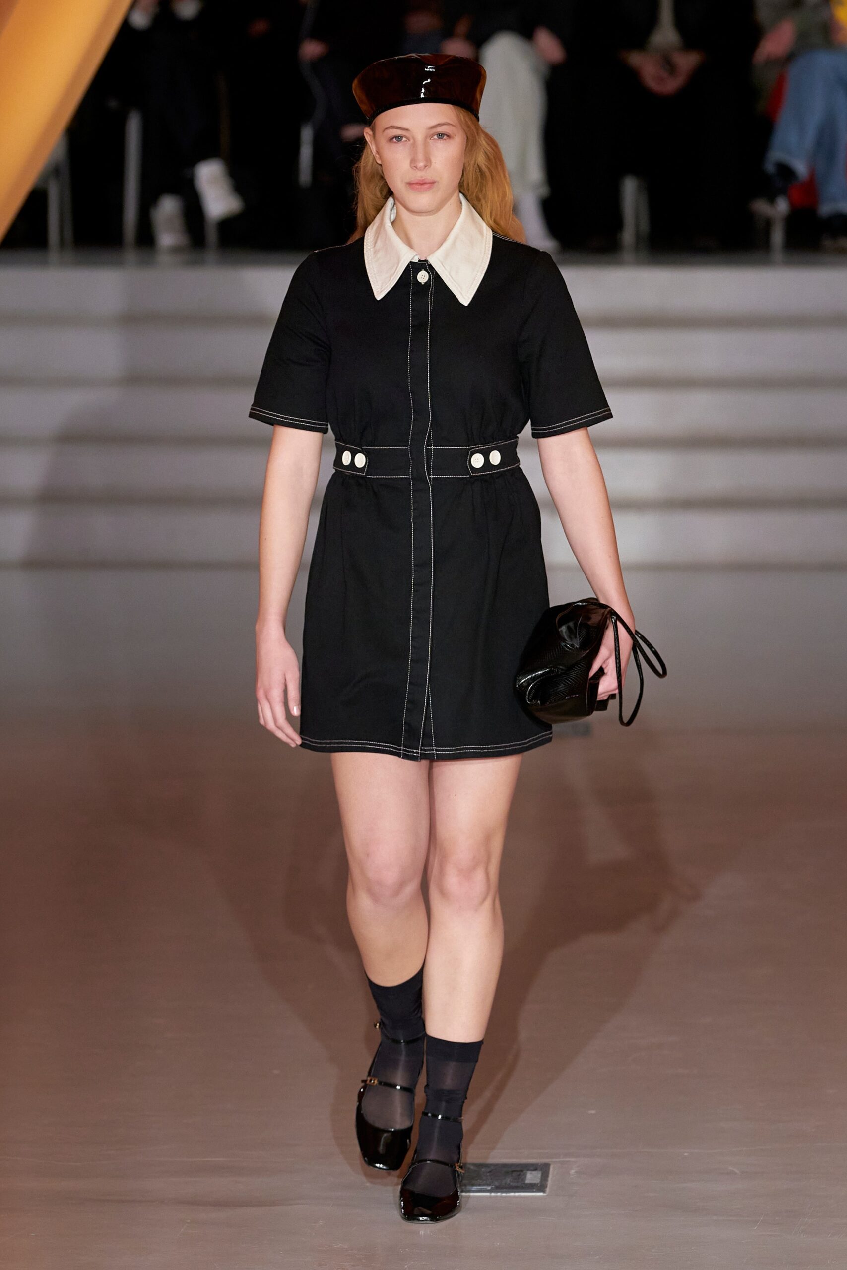 A fitted black denim dress with short sleeves and a collared neckline featuring button details.