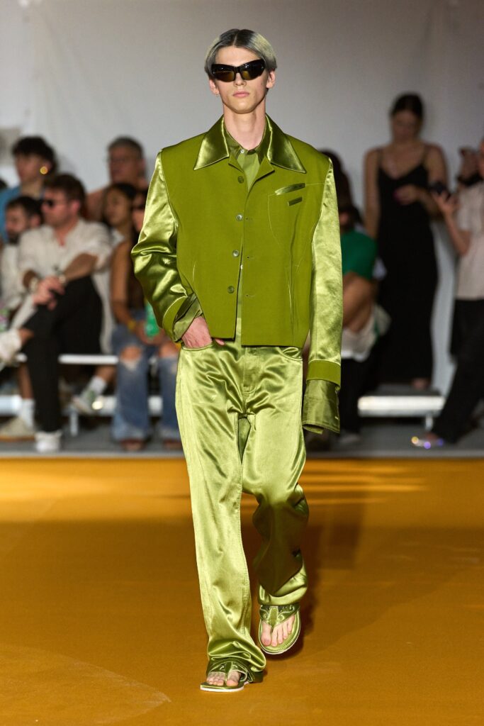 A fitted green silk jacket with long sleeves and collared design paired with straight-leg pants.