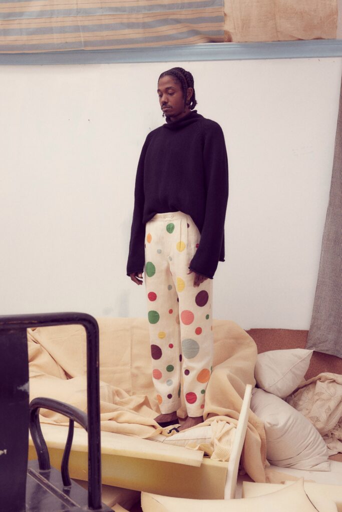 A relaxed black long-sleeve sweater paired with multicolor printed pants.