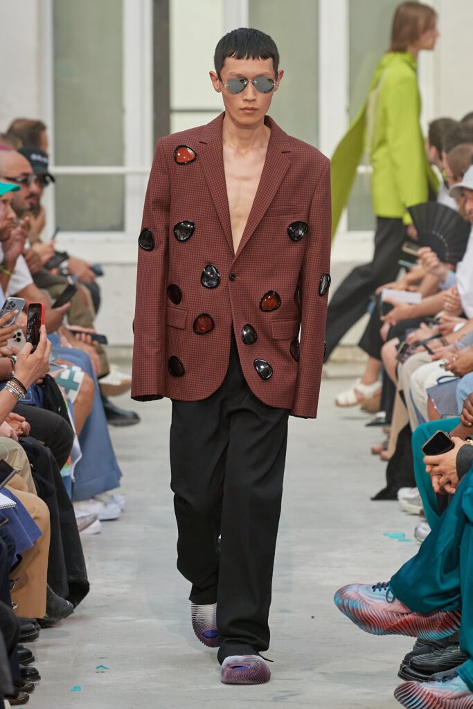 A relaxed brown buttoned jacket paired with black pants, featuring a layered design.
