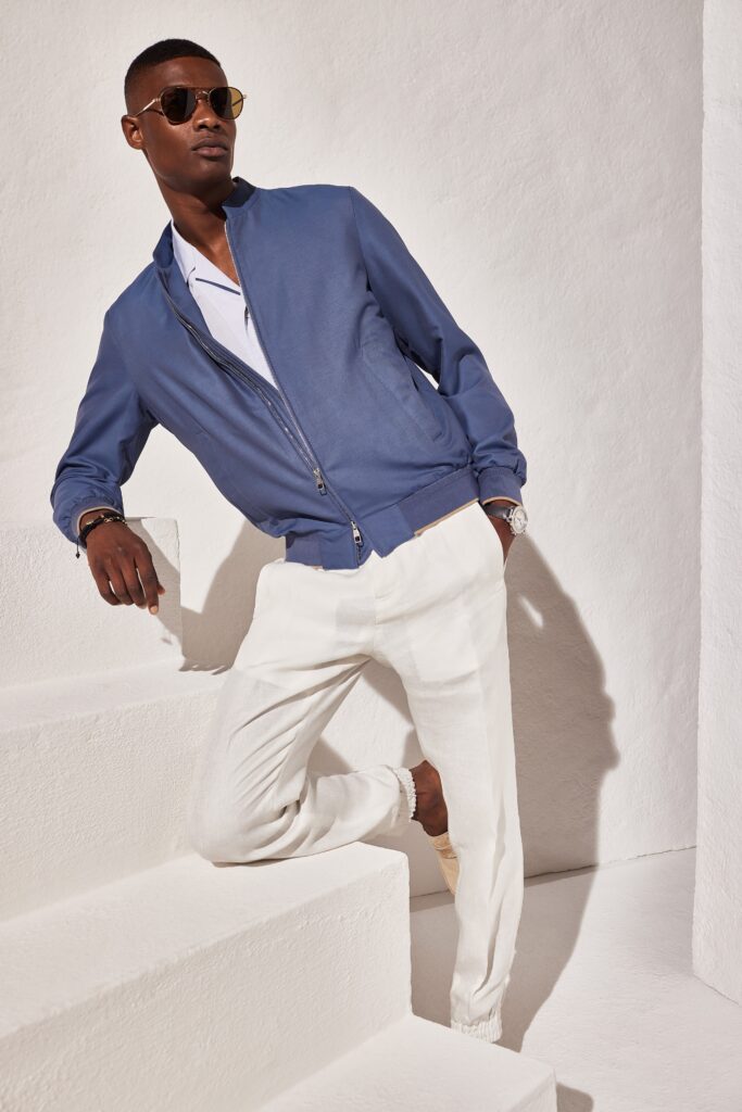 A relaxed blue cotton jacket paired with white pants, featuring a collared neckline and zippered detail.