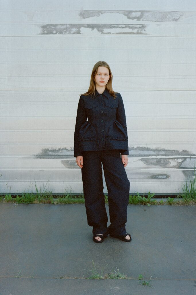 A relaxed black cotton jacket with long sleeves and pleated design paired with matching pants.