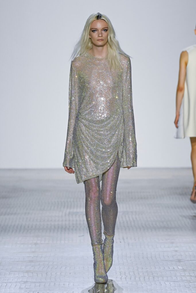 A fitted silver metallic long-sleeve dress with an asymmetric design and sheer details.