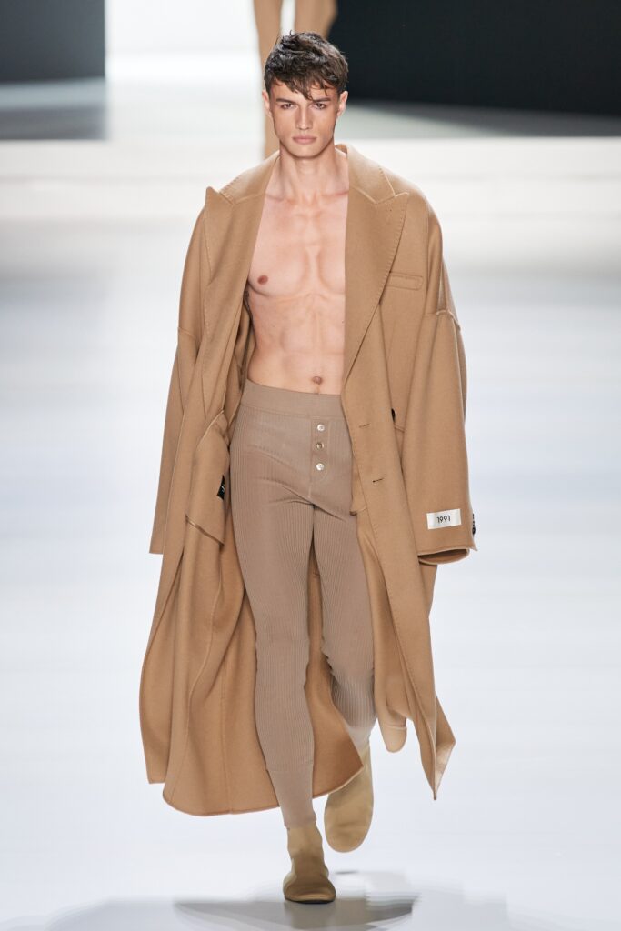 A fitted beige wool coat paired with high-waisted pants featuring button details.