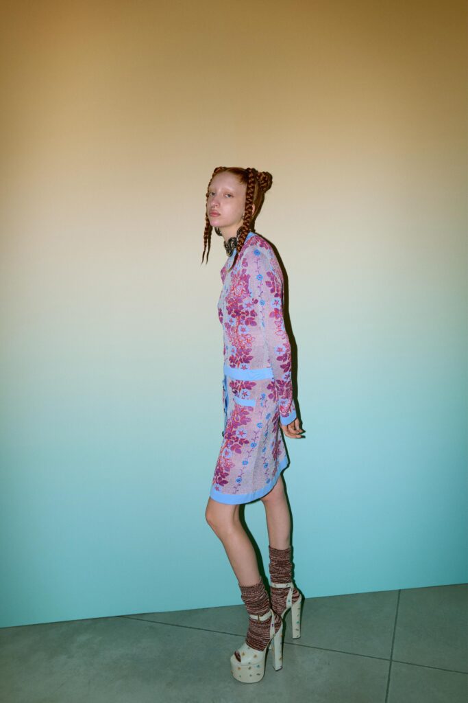 A fitted blue and pink floral dress with long sleeves and a collared neckline.