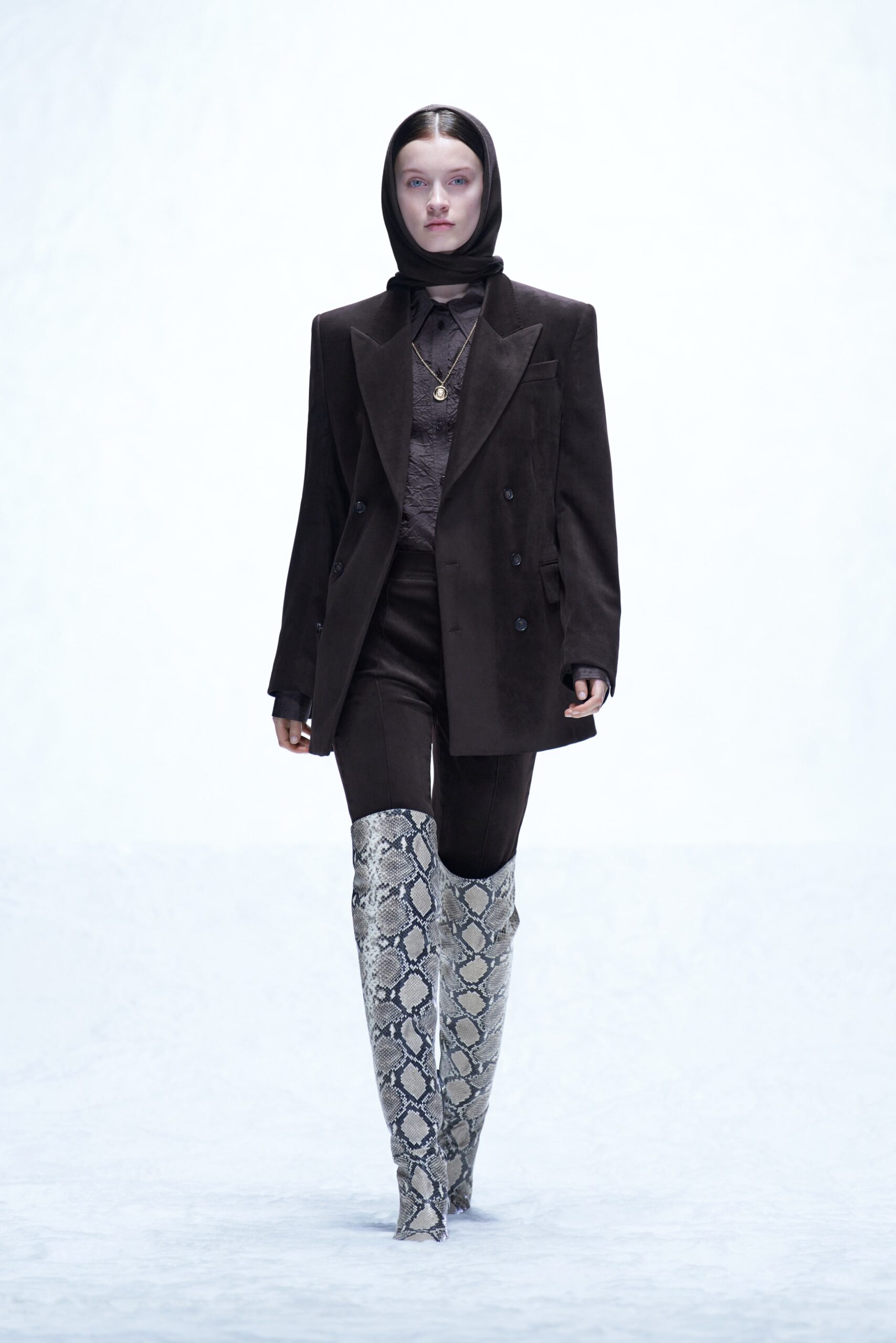 A fitted black blazer with long sleeves and collared neck paired with slim black pants.