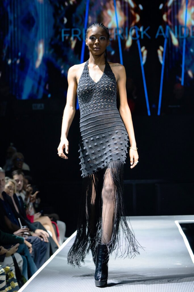 A fitted black sleeveless dress with a V-neckline and fringed detailing.