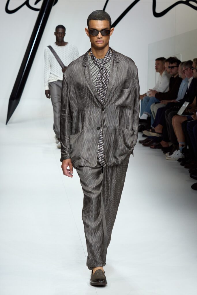 A tailored gray silk suit with long sleeves and a collared shirt featuring a striped pattern.