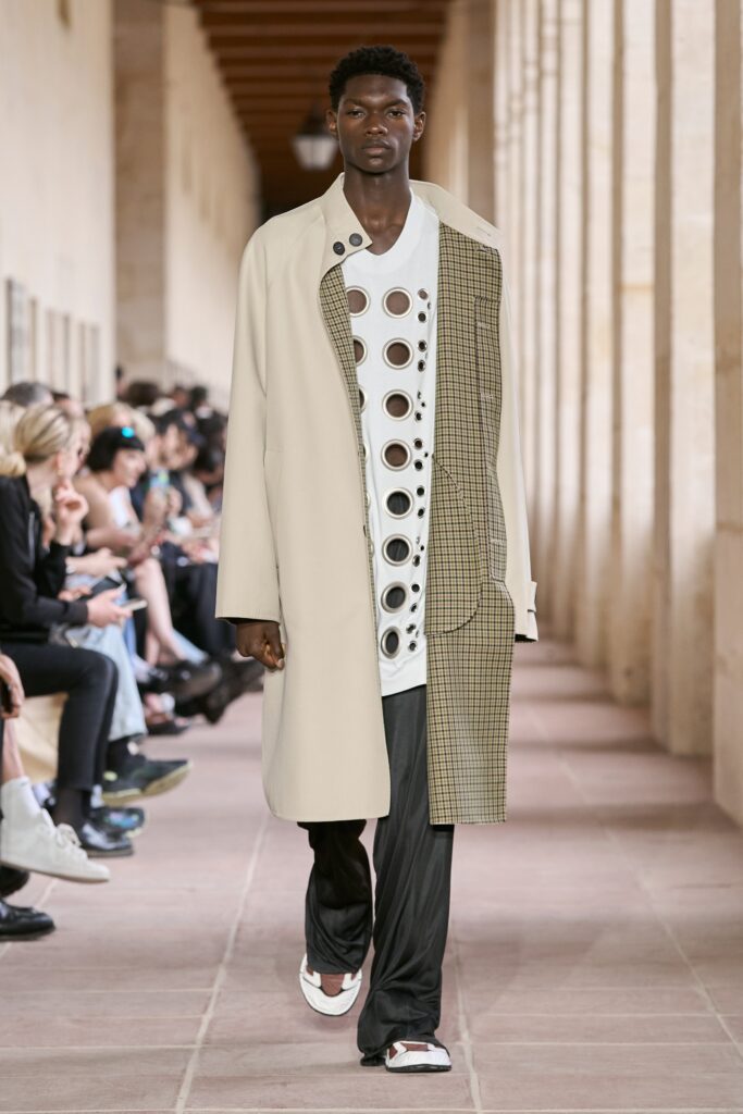 A relaxed beige coat layered over a white long-sleeve shirt with an asymmetric design.