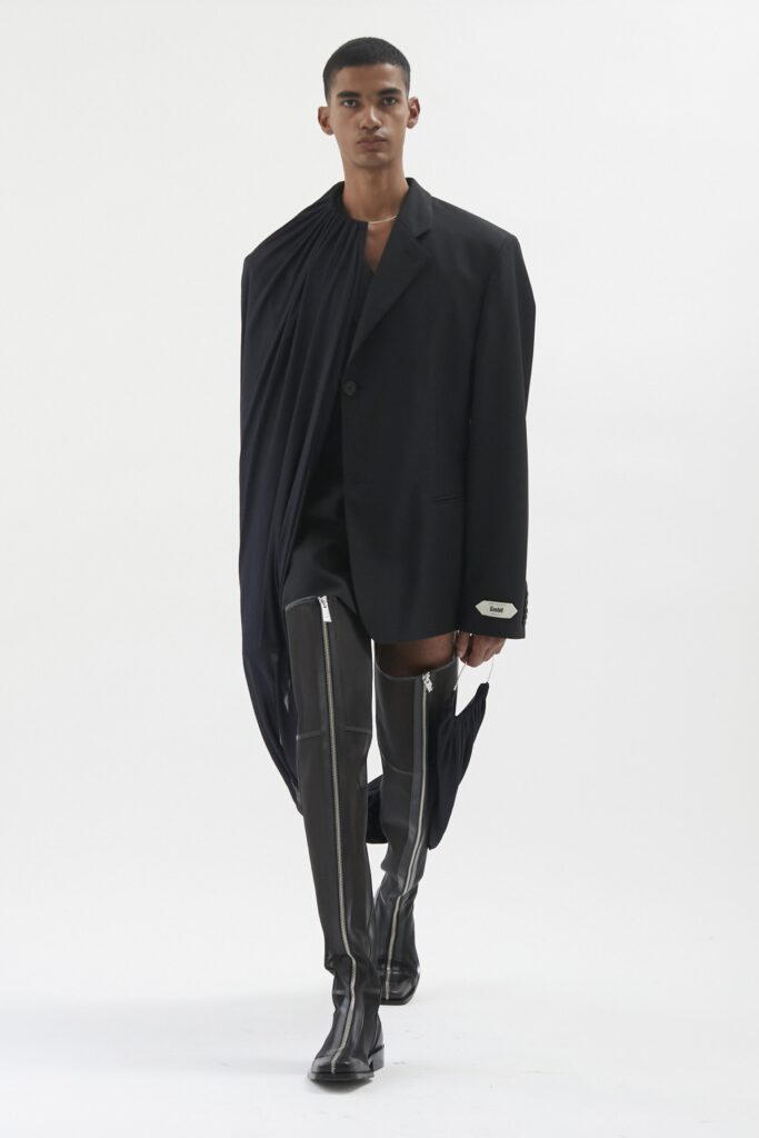 A fitted black jacket with an asymmetric design paired with sleek black pants.