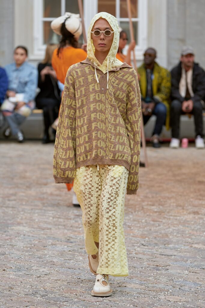 A relaxed brown printed hoodie paired with yellow pants, featuring a unique design.
