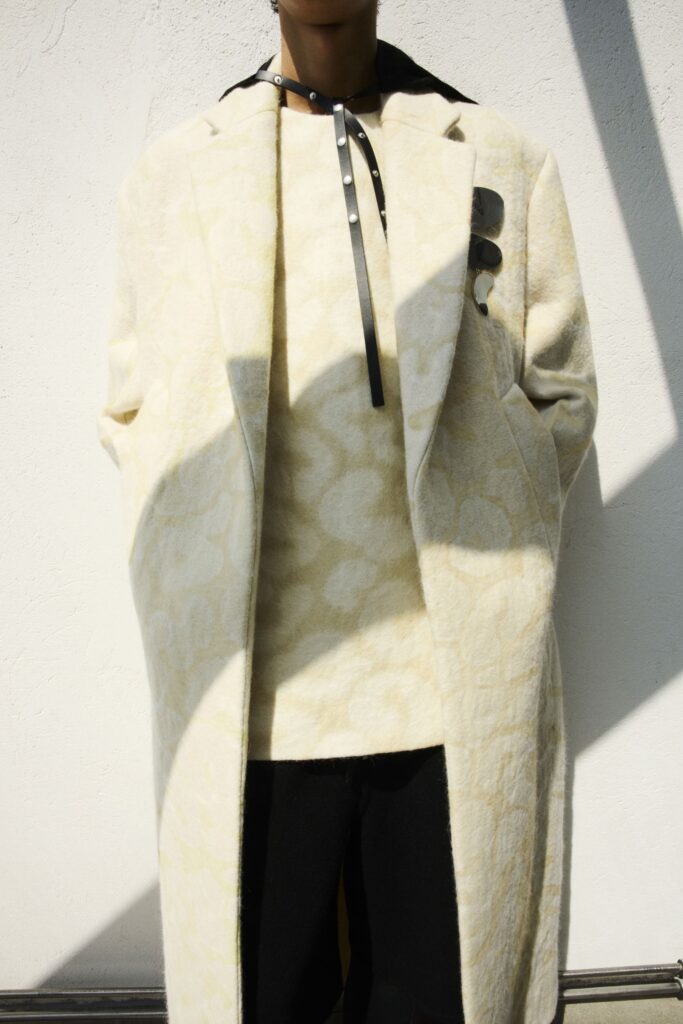 A relaxed cream wool coat layered over a black top with a collared design.