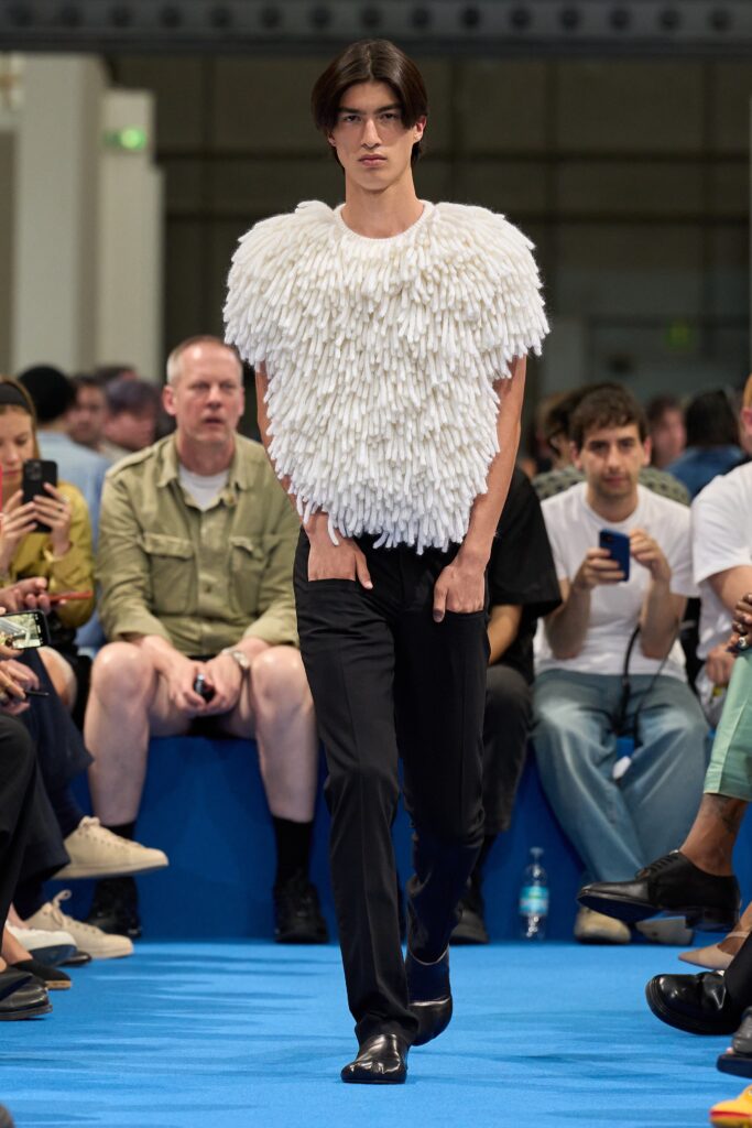 A fitted white textured sleeveless top paired with black pants for a modern look.