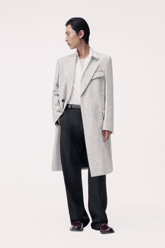 A relaxed white coat with a collared neckline and straight-leg black pants.