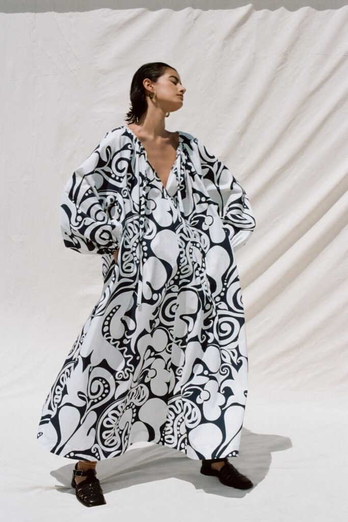 A relaxed black and white printed dress with a V-neckline and long sleeves.