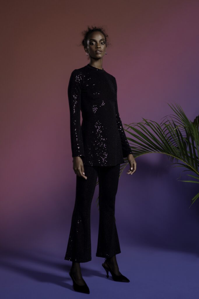 A fitted black sequin long-sleeve top paired with flared pants, creating a stylish silhouette.
