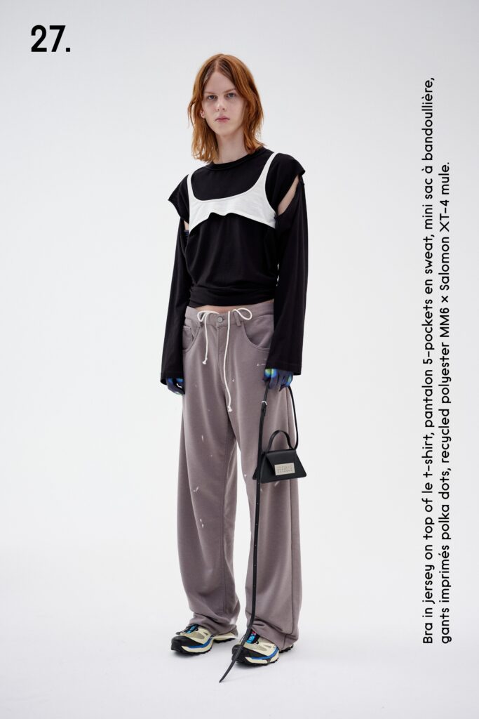 A relaxed black long-sleeve top layered over a white shirt paired with gray pants.
