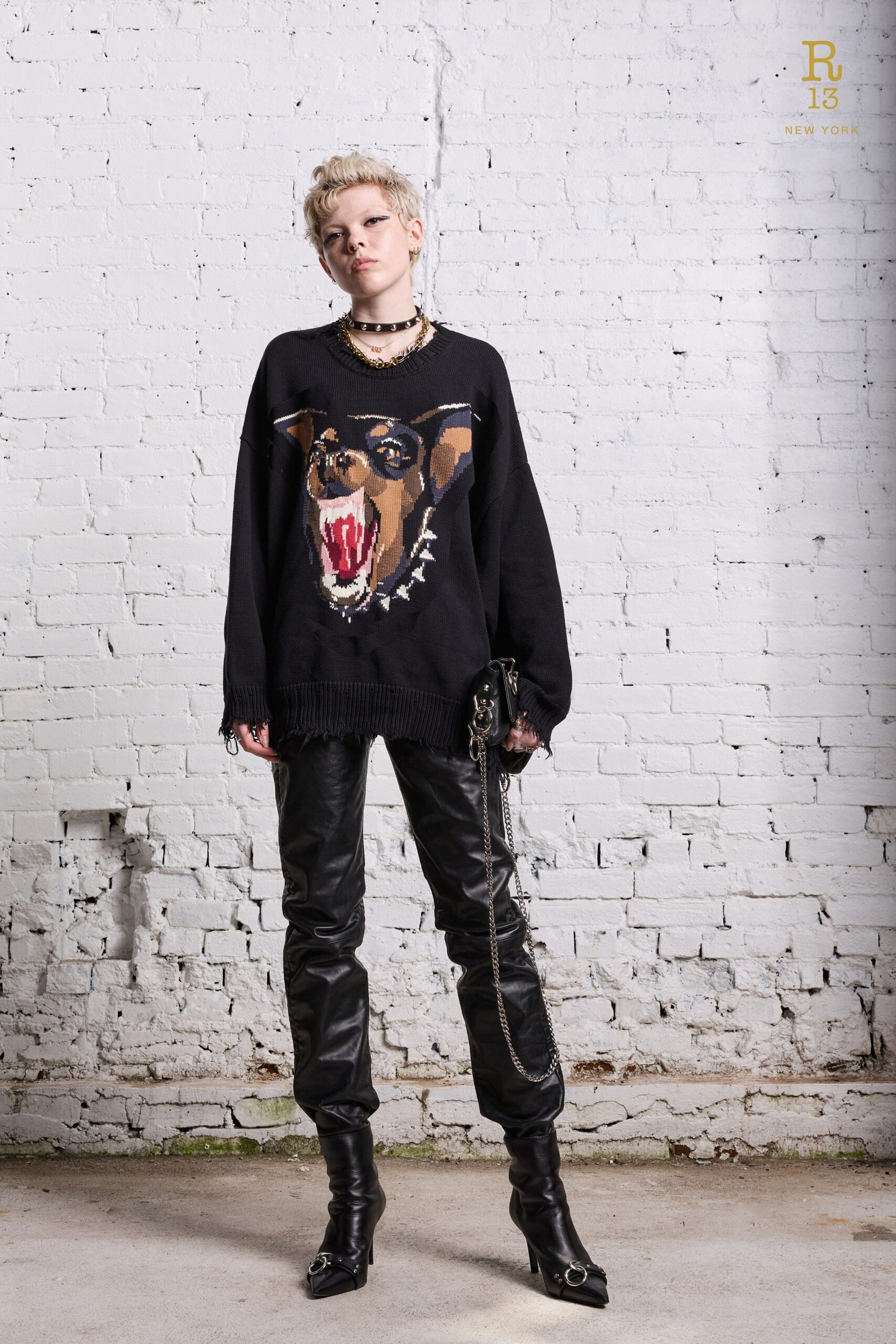 A fitted black sweater with a printed design paired with sleek black leather pants.