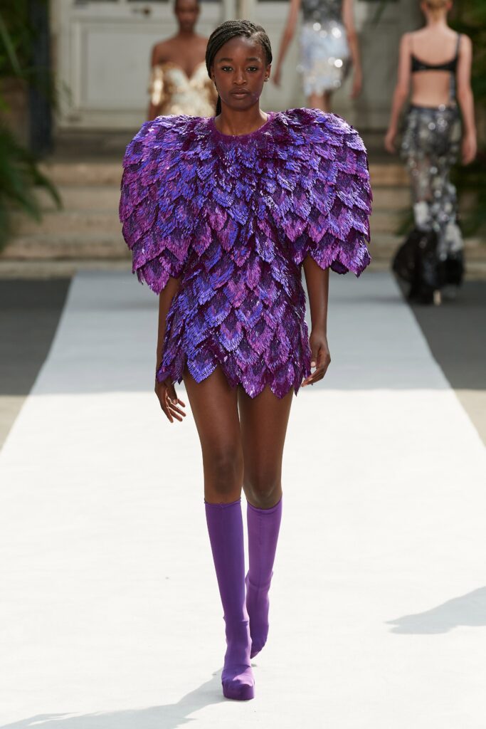 A fitted purple sequin dress with a high neckline and layered design detail.