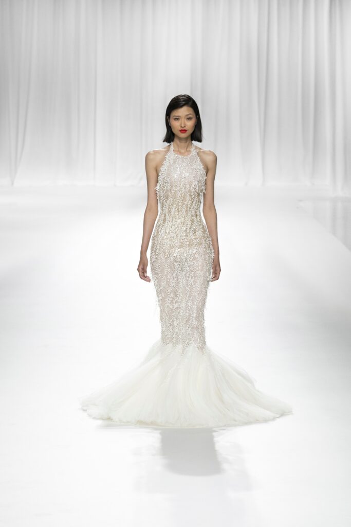 A fitted white silk gown with a high neckline and sequined mermaid silhouette.
