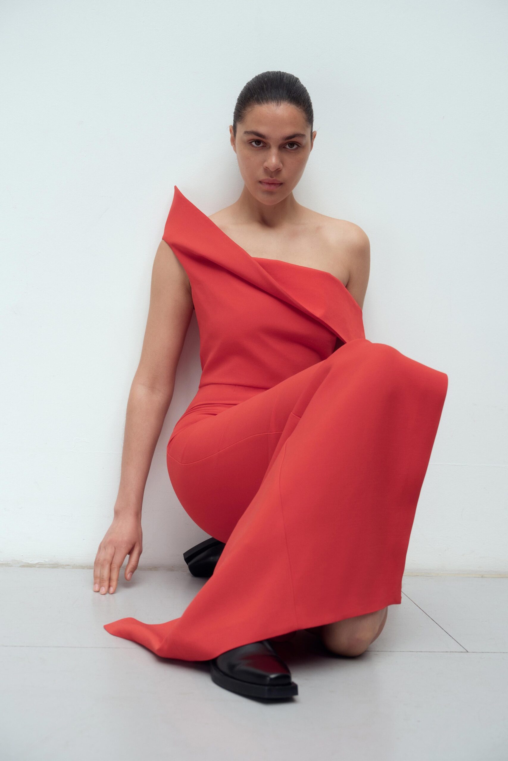 A fitted red silk dress with an asymmetric design and a stylish slit.