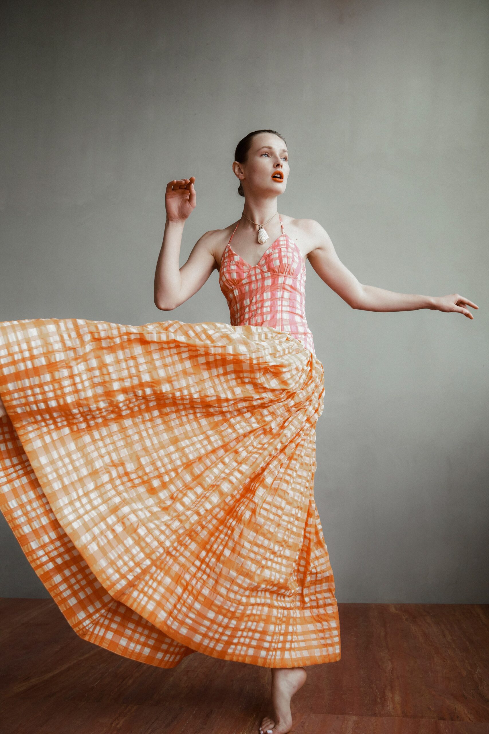 A fitted sleeveless dress in orange and pink with a V-neckline and tiered design.