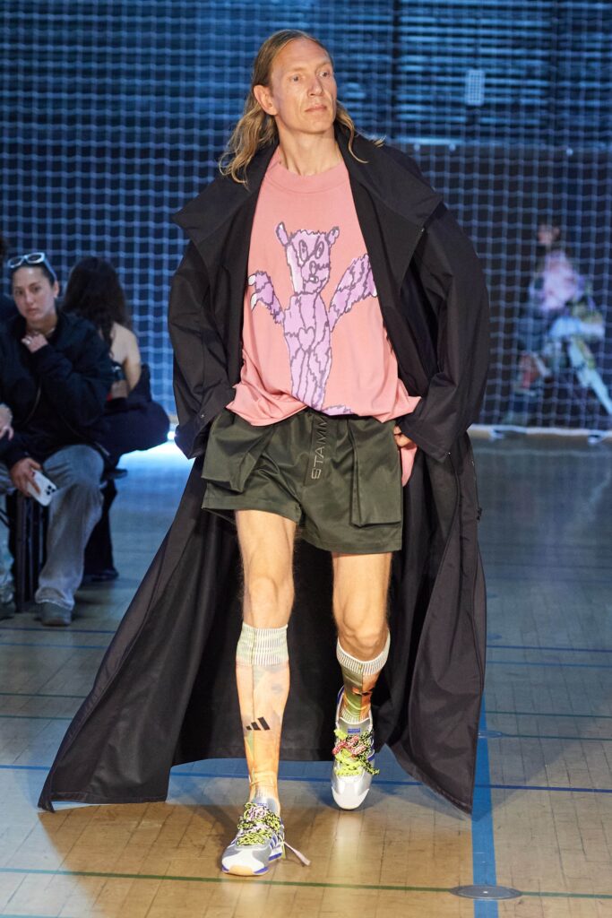 A relaxed black coat layered over a short-sleeve pink printed shirt.