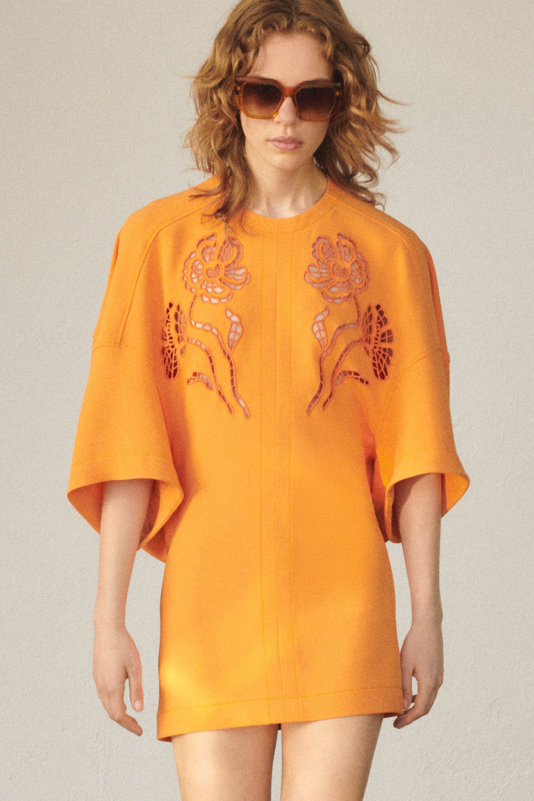 A relaxed orange silk dress with short sleeves and embroidered floral details.