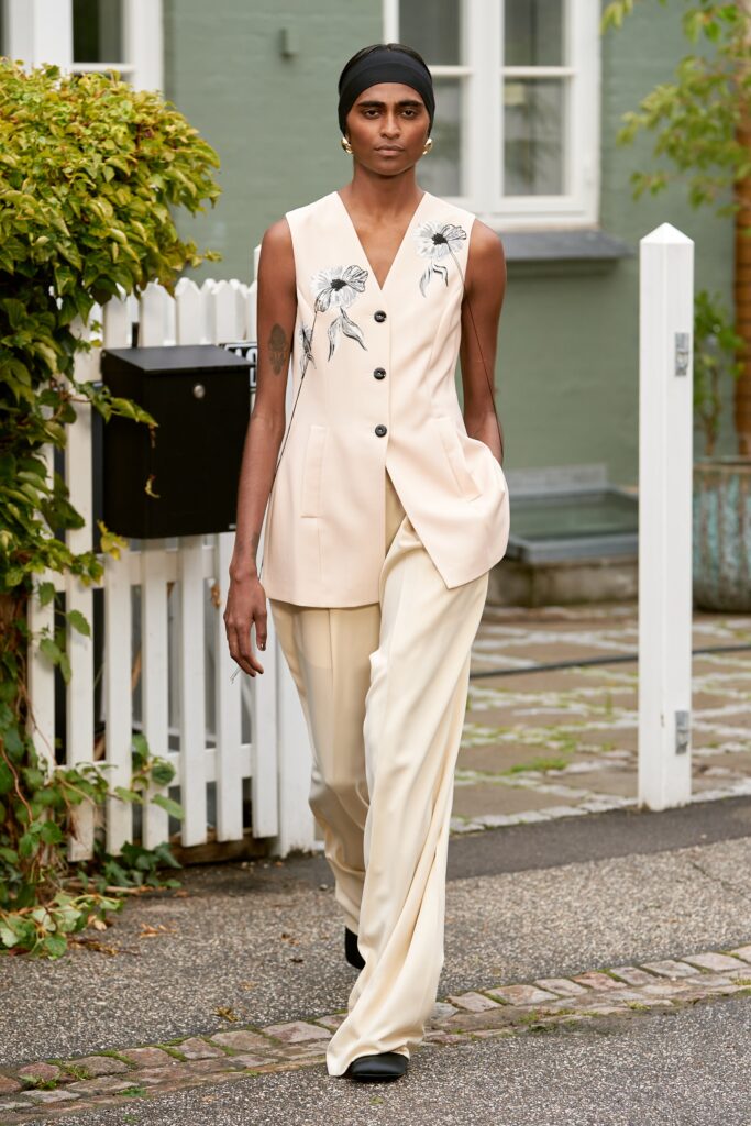 A relaxed beige cotton sleeveless vest with embroidery paired with wide-leg pants.