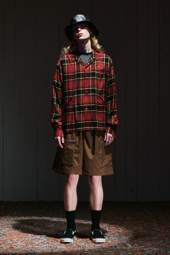 A relaxed long-sleeve plaid shirt paired with high-waisted brown shorts.