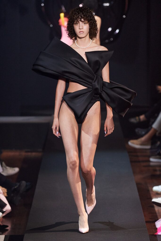 A fitted black silk off-shoulder dress with an asymmetric design detail.
