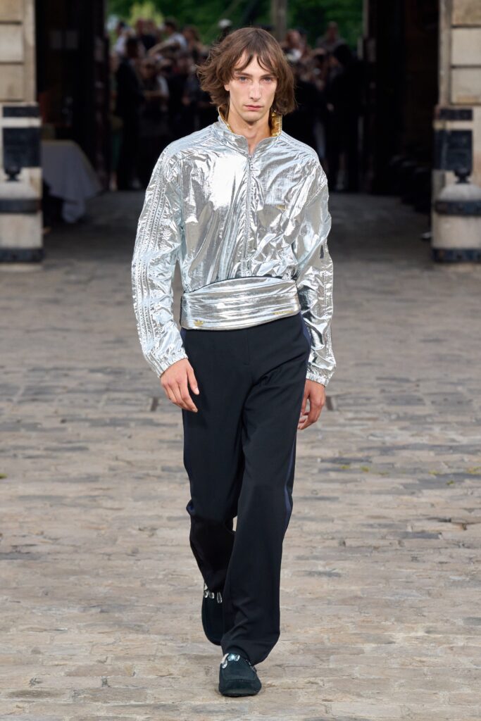 A relaxed silver metallic jacket paired with black pants featuring a zippered design.