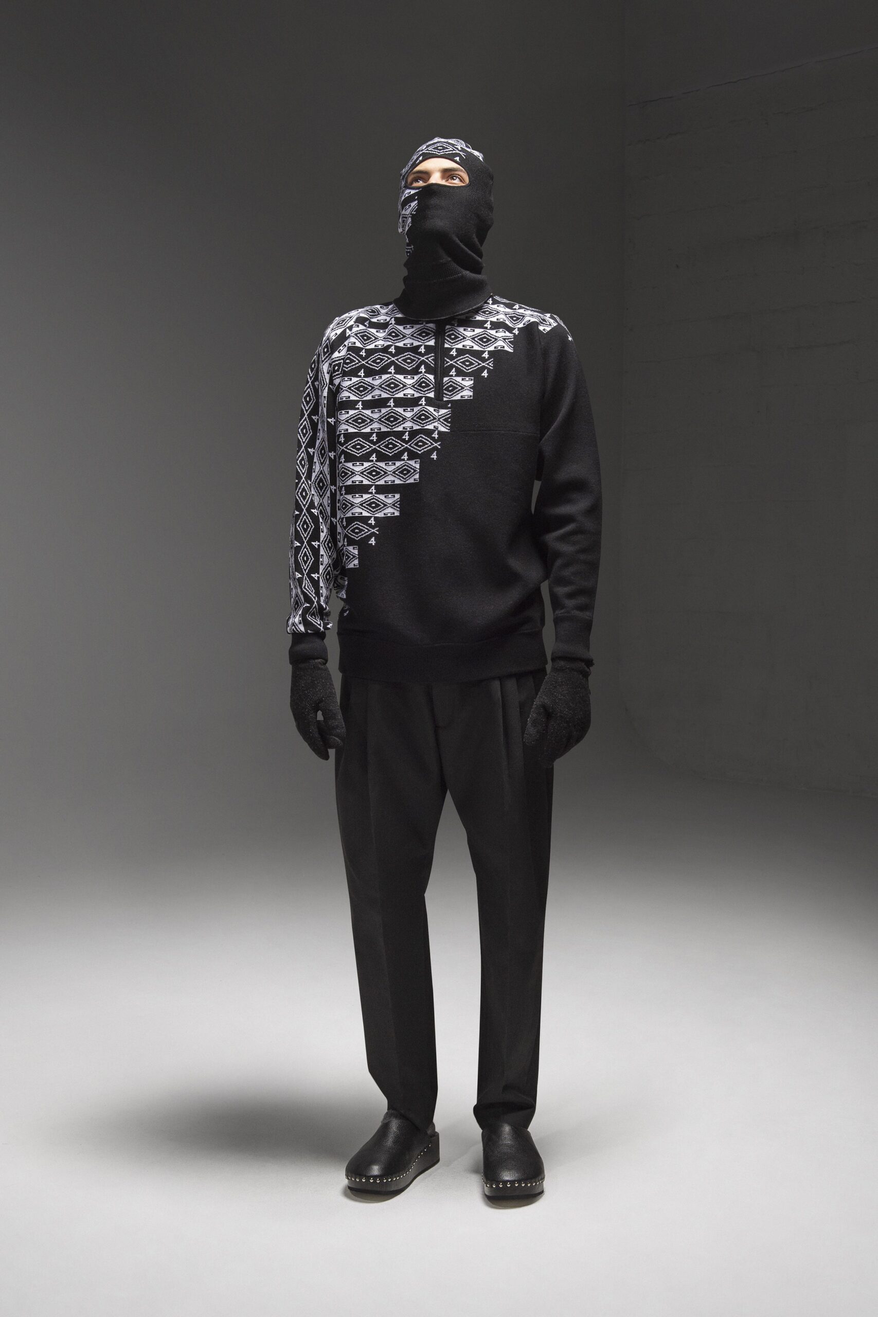 A relaxed black long-sleeve sweater with a printed design paired with black pants.