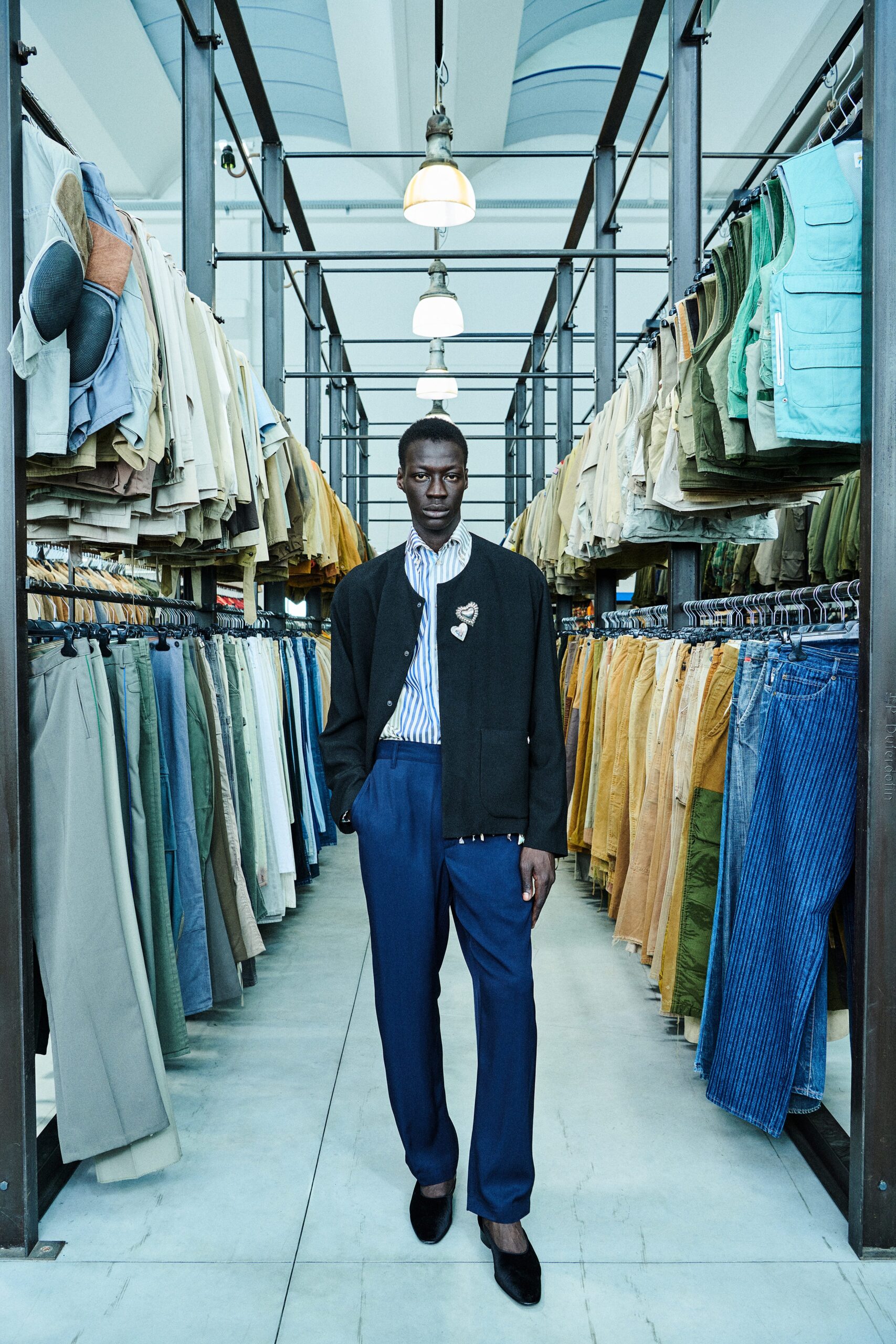 A tailored black jacket paired with blue straight-leg pants and a collared shirt.