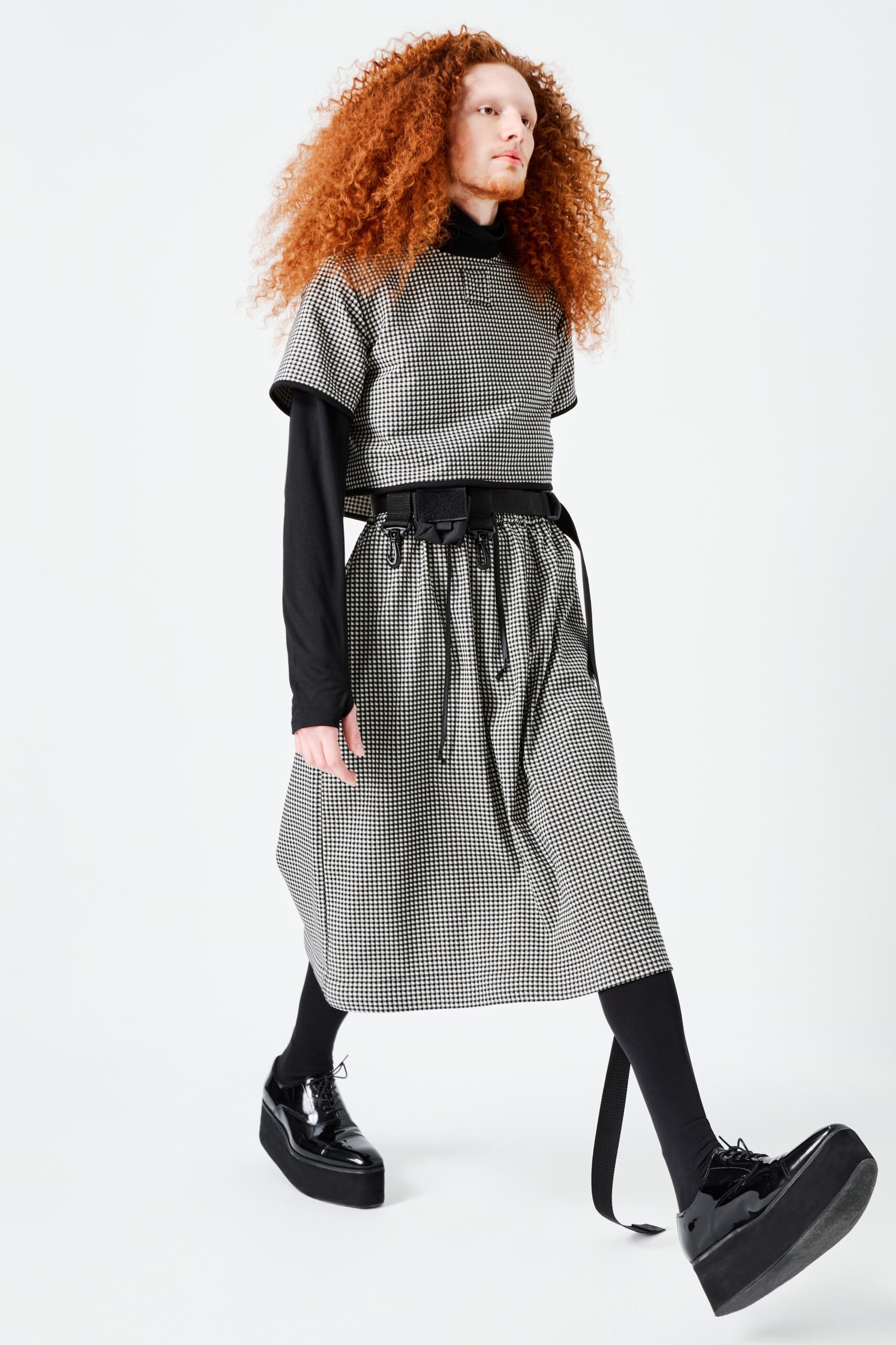 This relaxed dress features a distinctive black and white checked pattern, enhanced by a belted waist that defines its silhouette. The short sleeves and collared neckline add a contemporary touch, creating a modern yet timeless appeal.