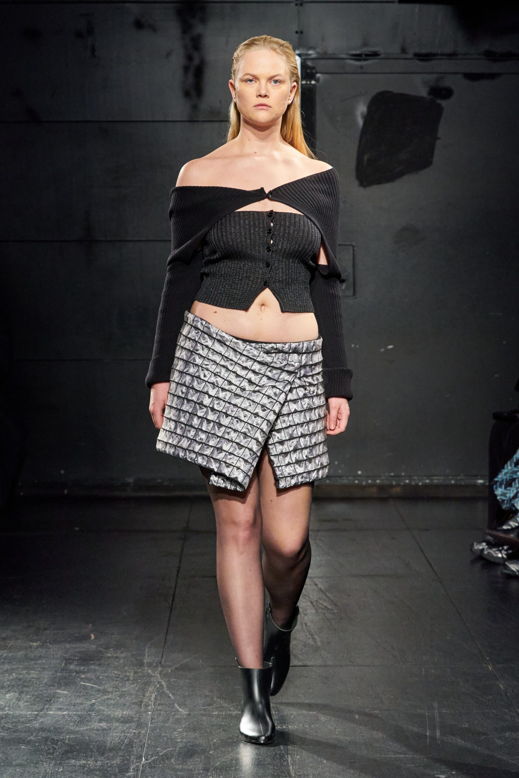 A fitted black long-sleeve cropped top paired with an asymmetric gray skirt.