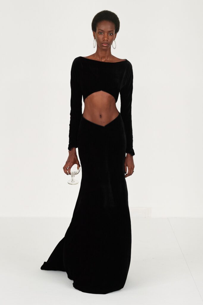 A fitted black velvet dress with long sleeves, off-shoulder design, and a flared silhouette.