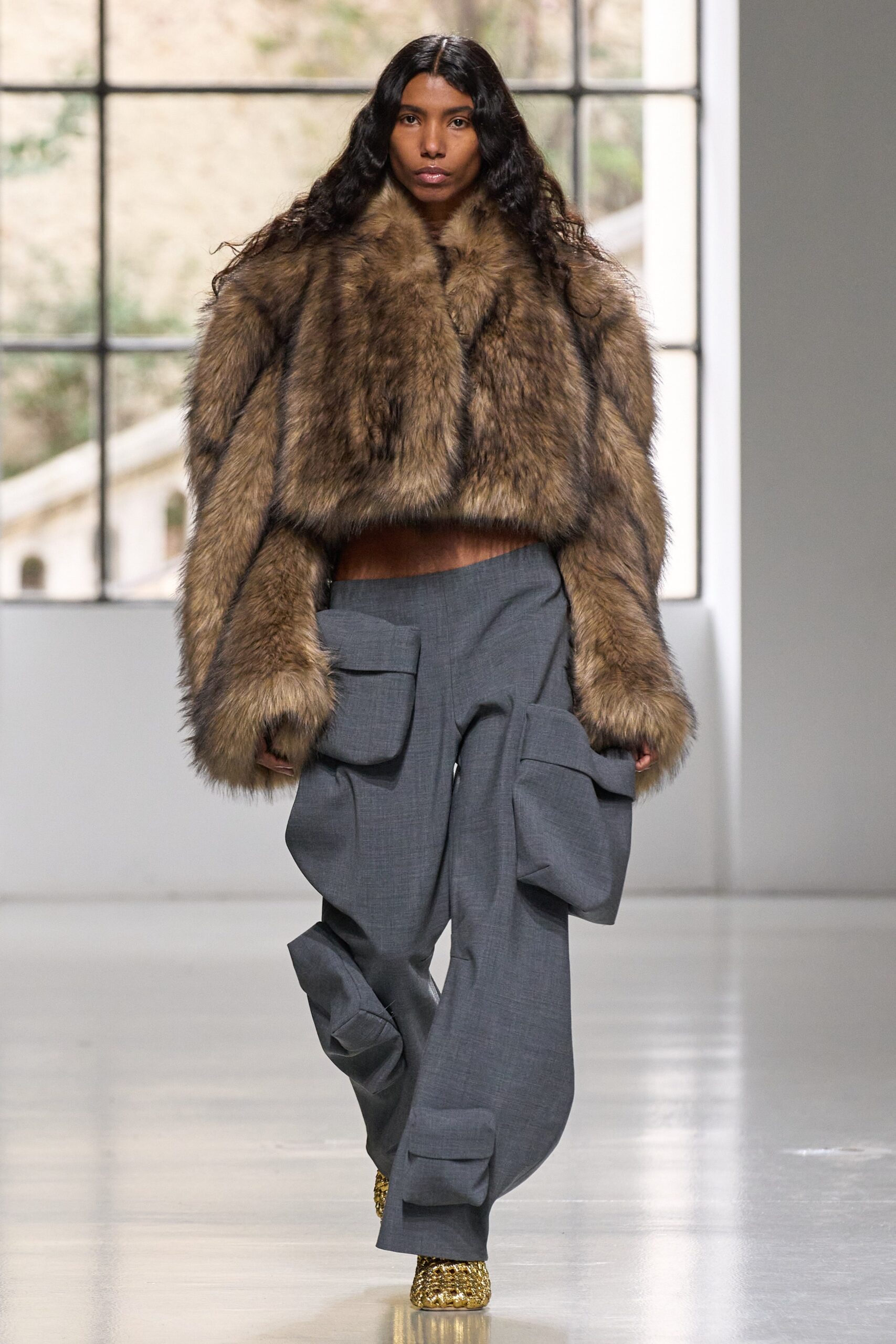 A relaxed brown fur coat paired with gray cotton pants featuring a layered design.