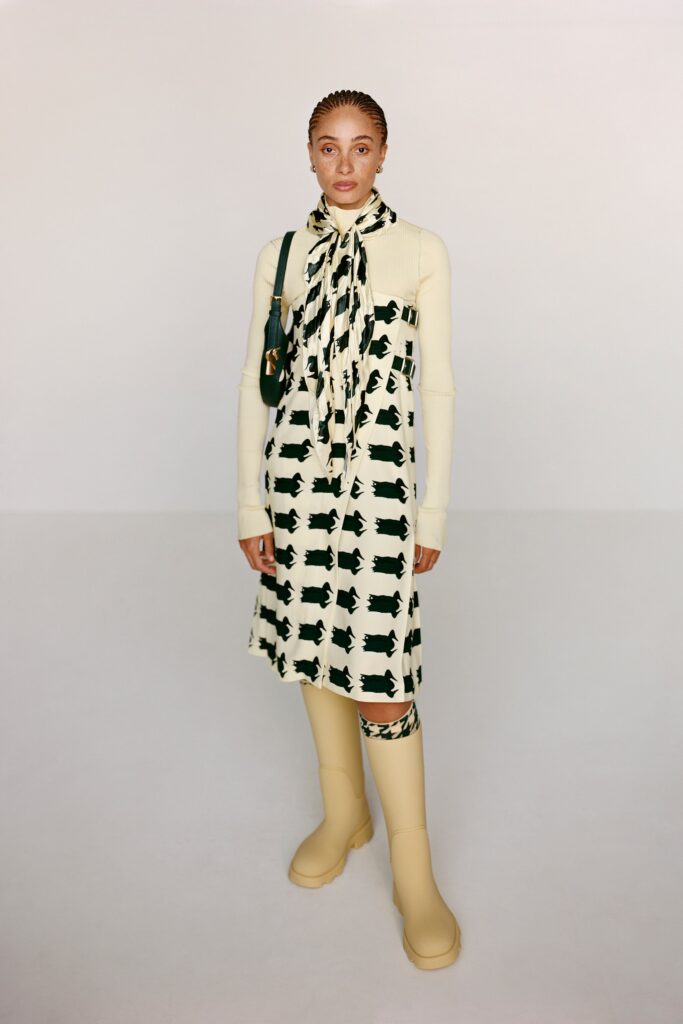 A fitted cream dress with long sleeves and a collar, featuring a black print design.