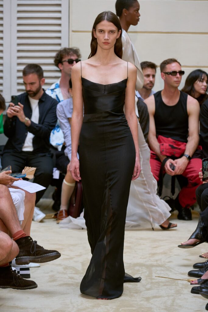 A fitted black silk sleeveless dress with a V-neckline and a stylish slit.