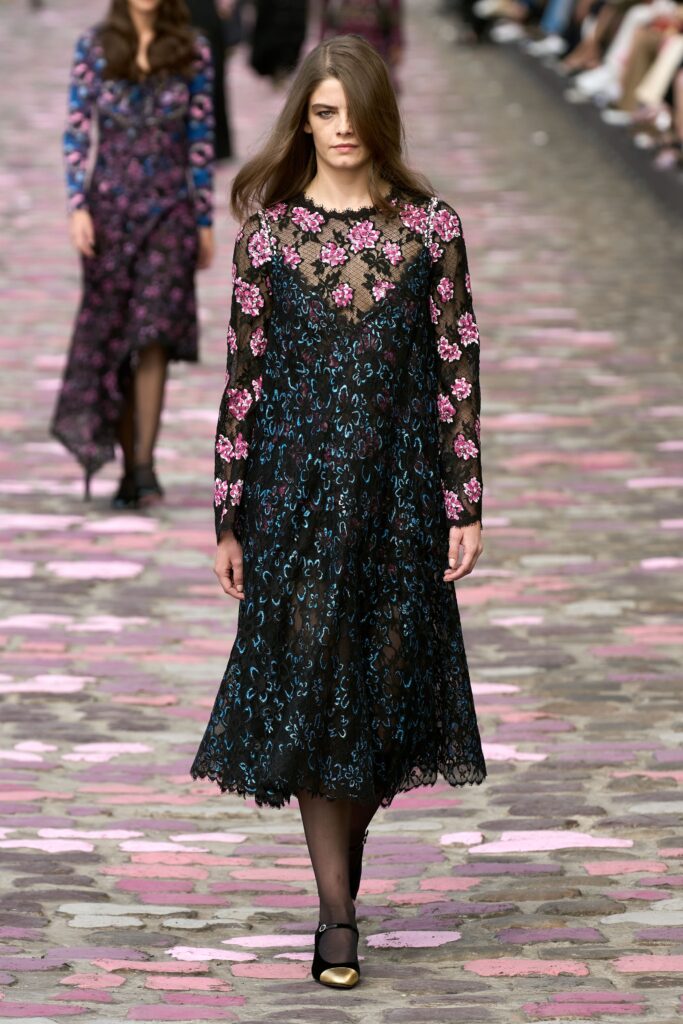 A fitted black lace long-sleeve dress with a V-neckline and flared silhouette.